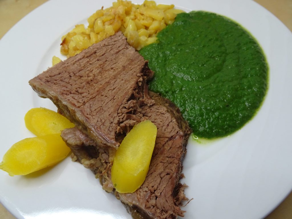 Spinat mit Erdäpfeln und Rindfleisch auf weißem Teller