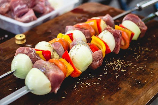 Close-up of freshly prepared barbecue skewers with meat and veggies on a wooden board.