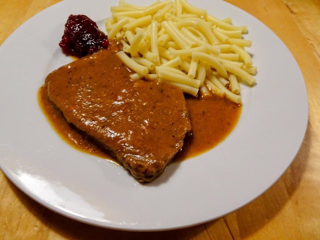 Gedünstete Rindschnitzel mit Makkaroni und Preiselbeeren auf weißem Teller