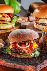 delicious burgers on wooden boards on table
