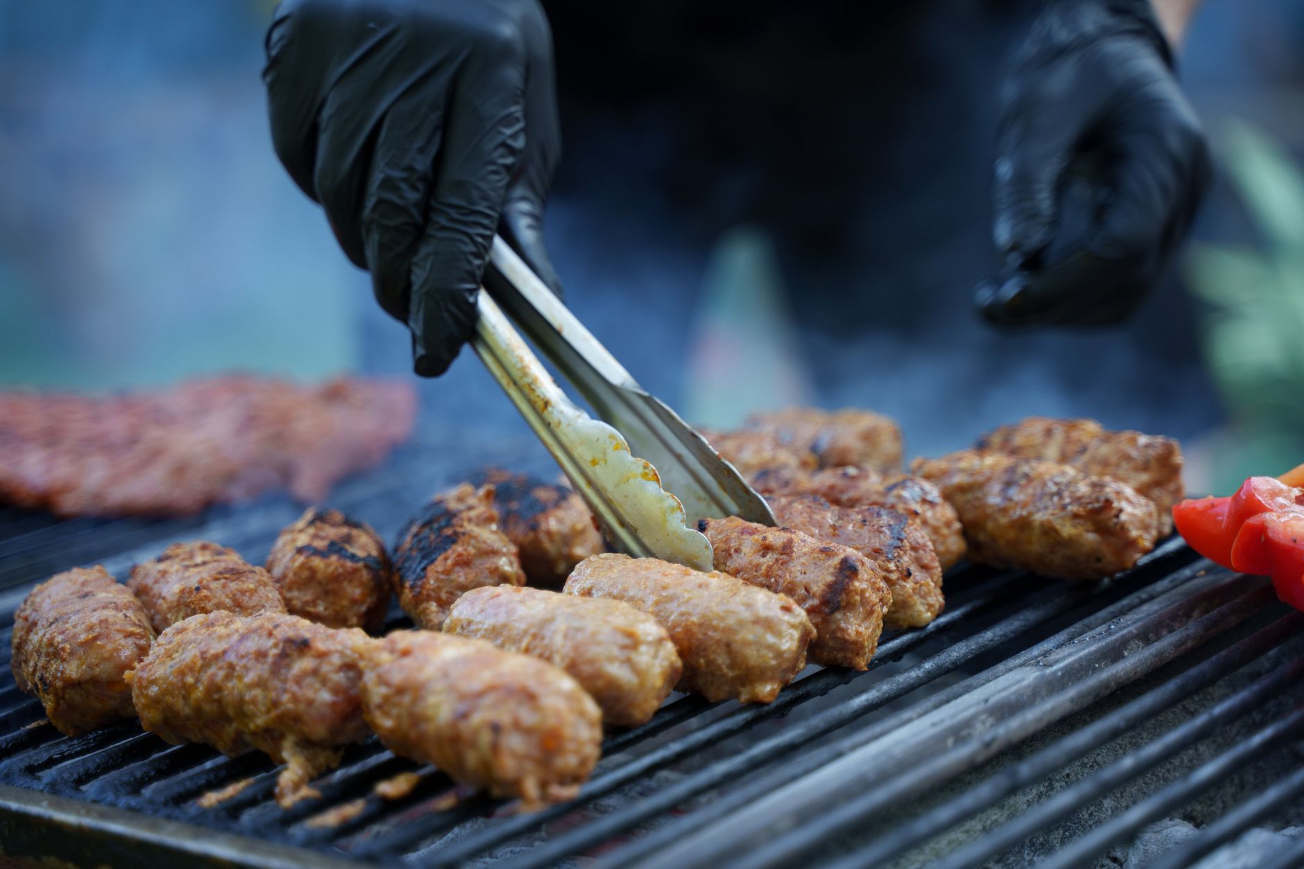 close up of a person turning the meat on a grill grid