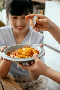 crop women having homemade pasta for dinner