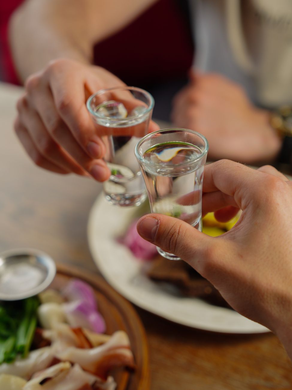 hands holding glasses over table