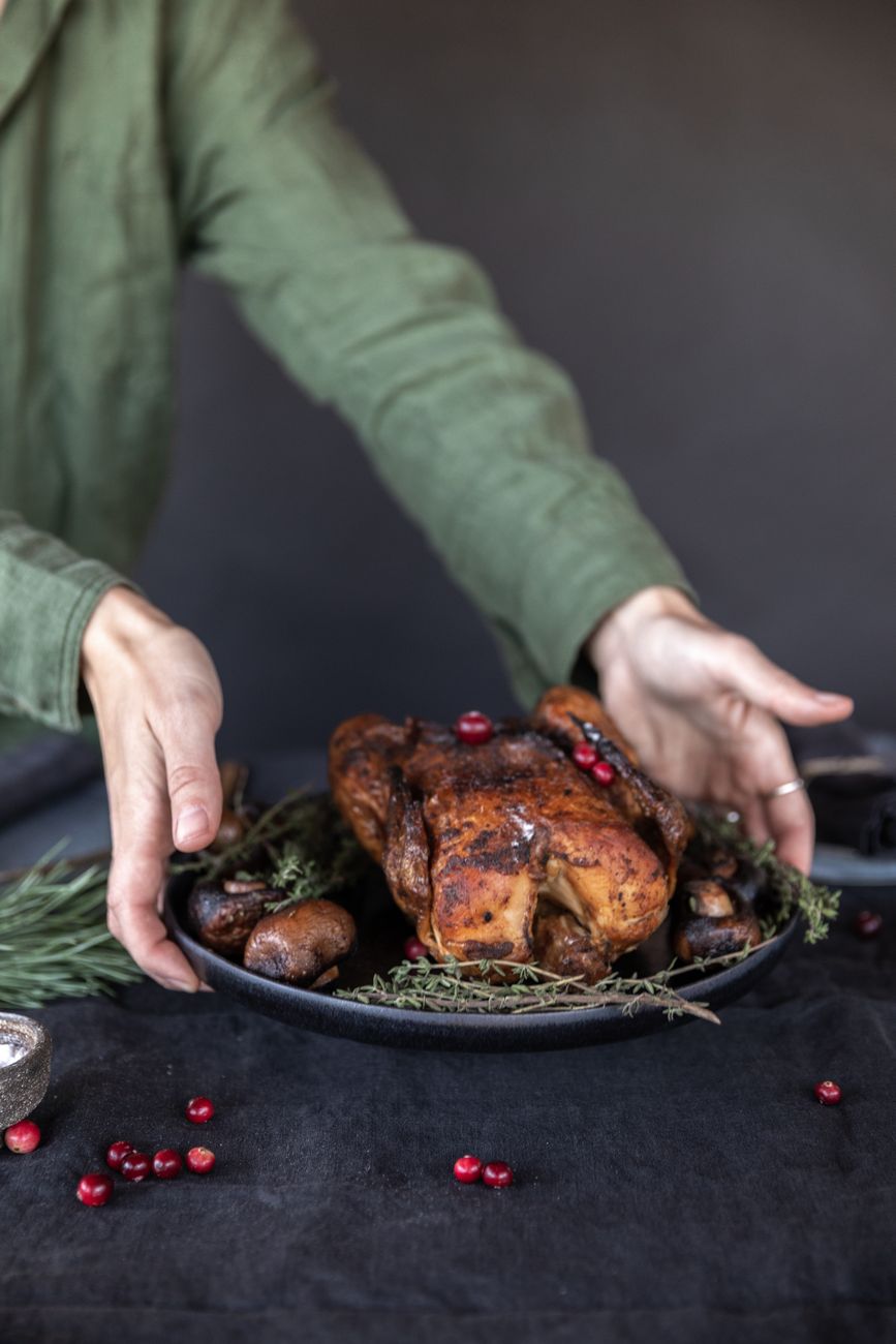 person holding black ceramic plate with cooked turkey