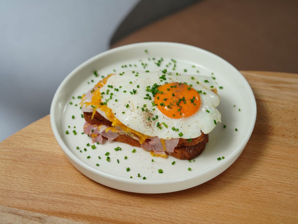 plate with croque madame sandwich standing on a wooden table
