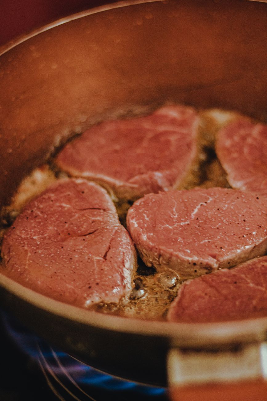 close up photo of meat cooking in frying pan