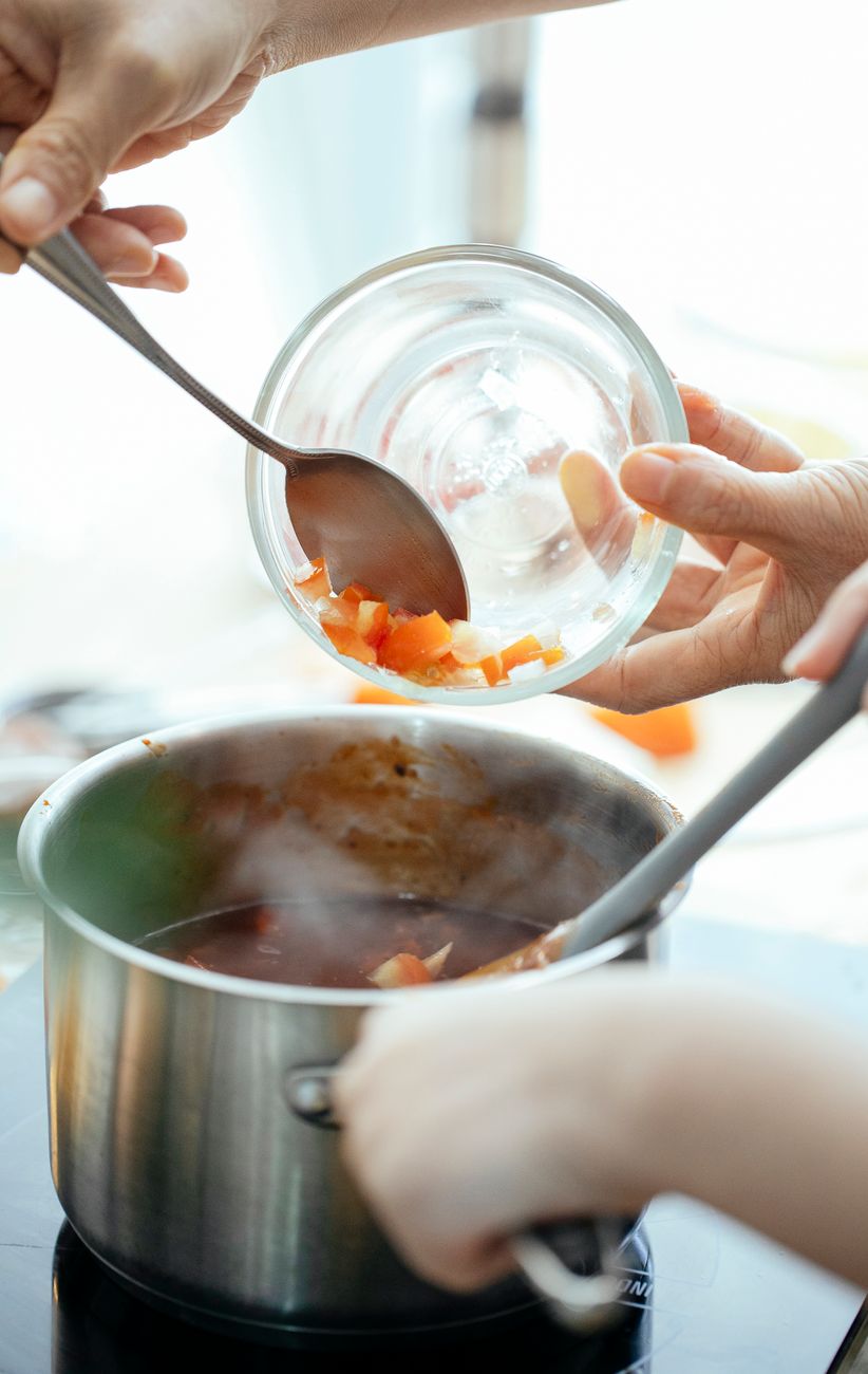 crop person adding tomatoes into pan
