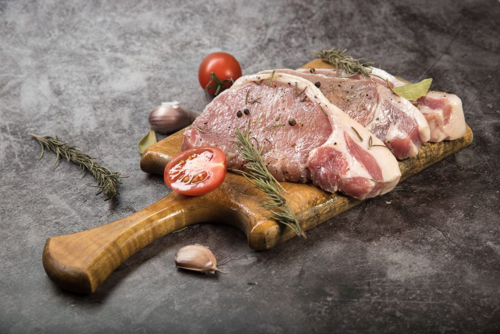 raw meat slices on wooden chopping board