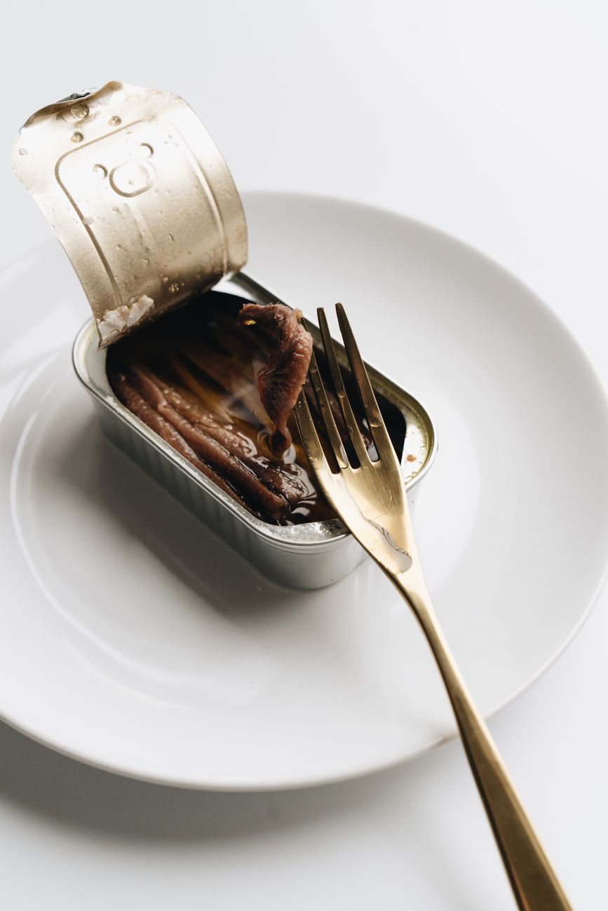 a fork with anchovy on a can