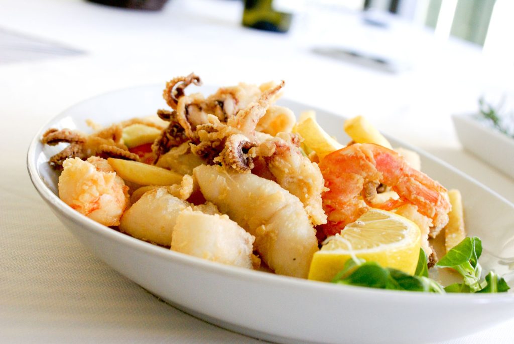 deep fried shrimp and squid with slice of lemon on ceramic plate