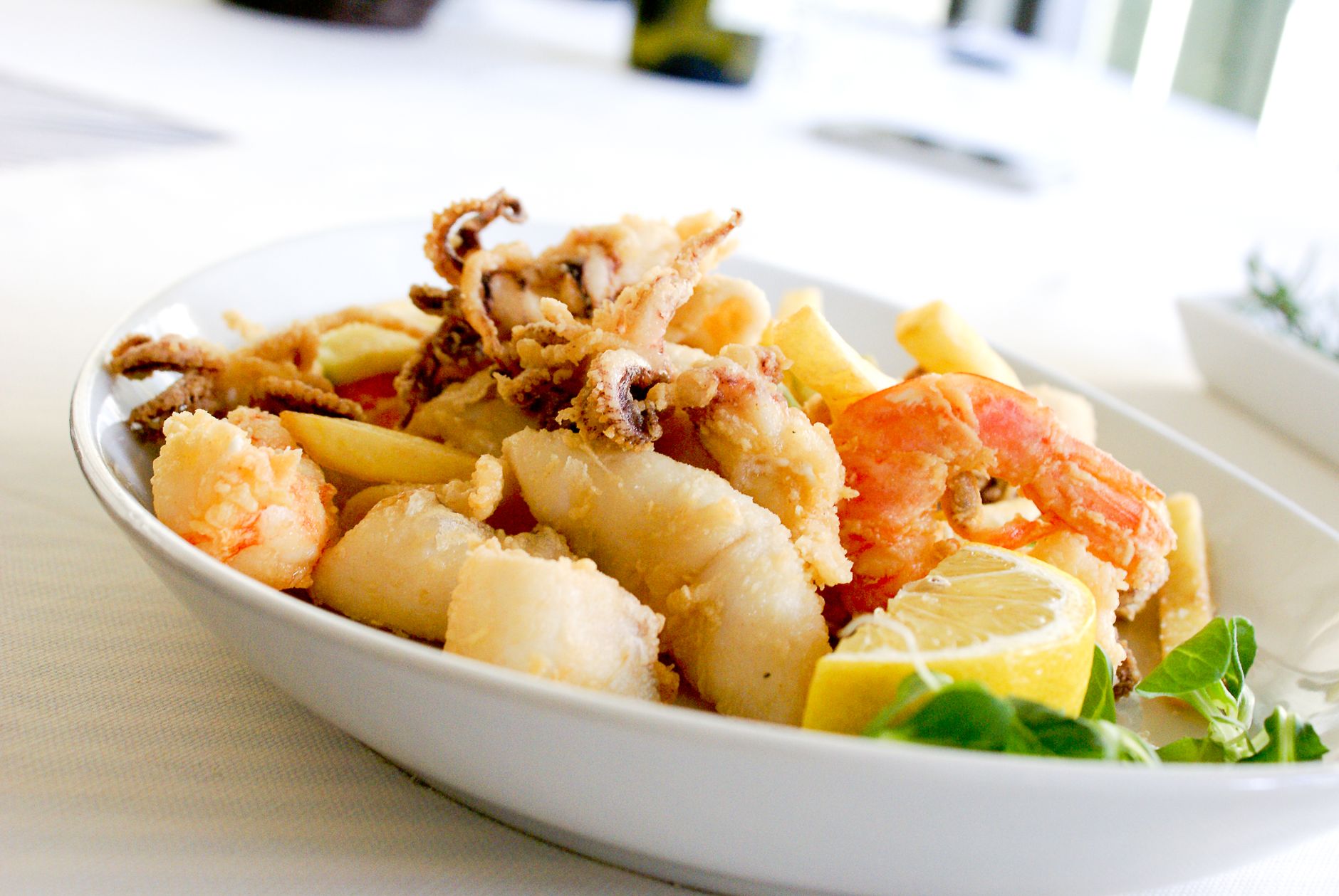 deep fried shrimp and squid with slice of lemon on ceramic plate